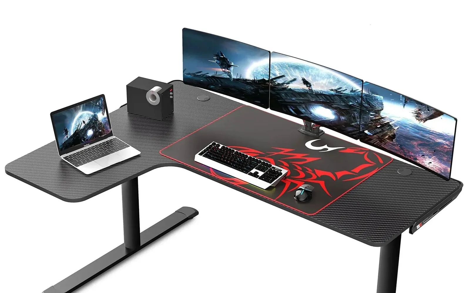 Black L-shaped gaming desk with a carbon fiber surface, a large mouse pad, three monitors on an arm and a laptop on the side wing
