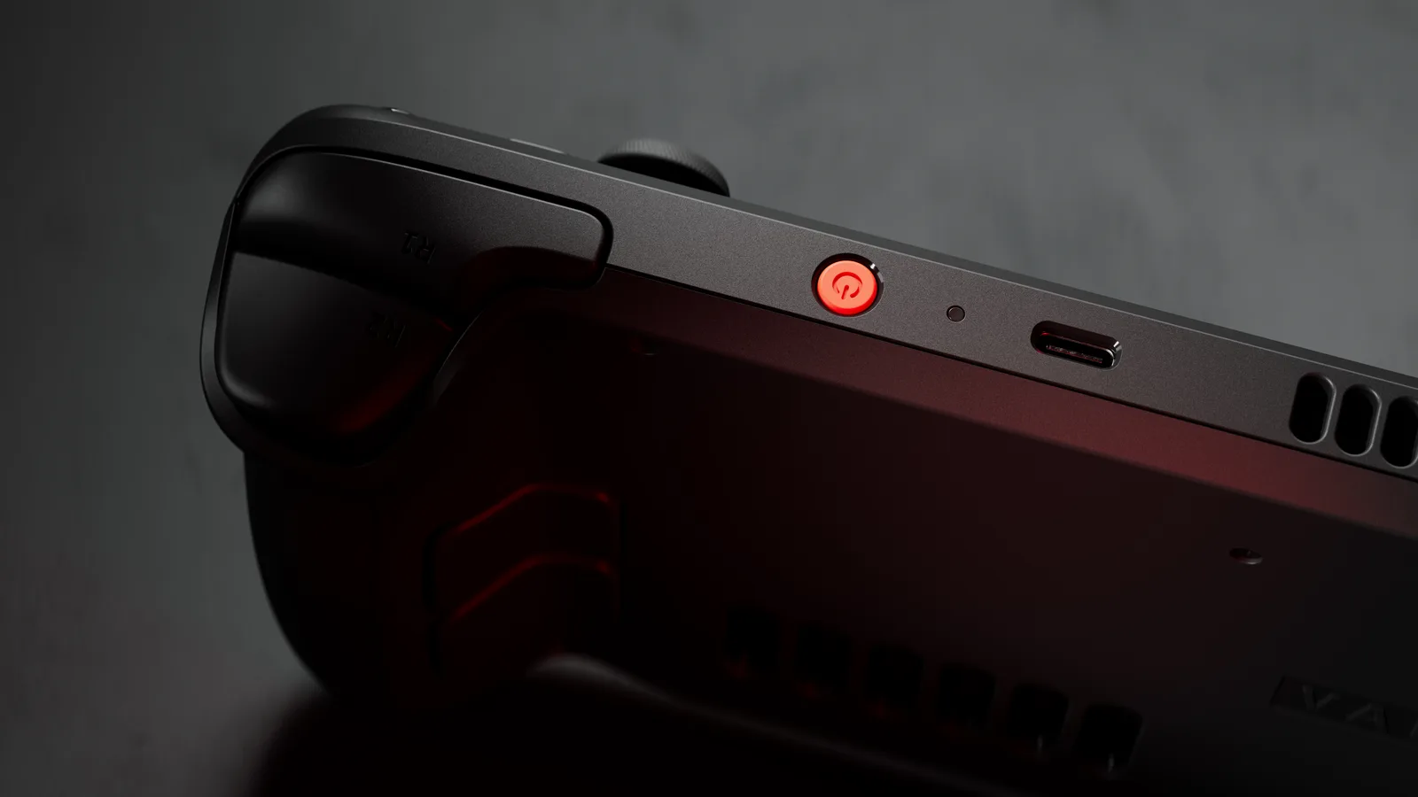 Close-up of the Steam Deck OLED top edge, with the glowing power button and the USB-C charging port